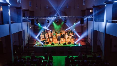 Chor im Scheinwerferlicht auf einer Bühne in einem großen Saal